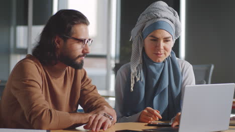 Businesswoman-in-Hijab-Speaking-with-Male-Colleague-in-Office